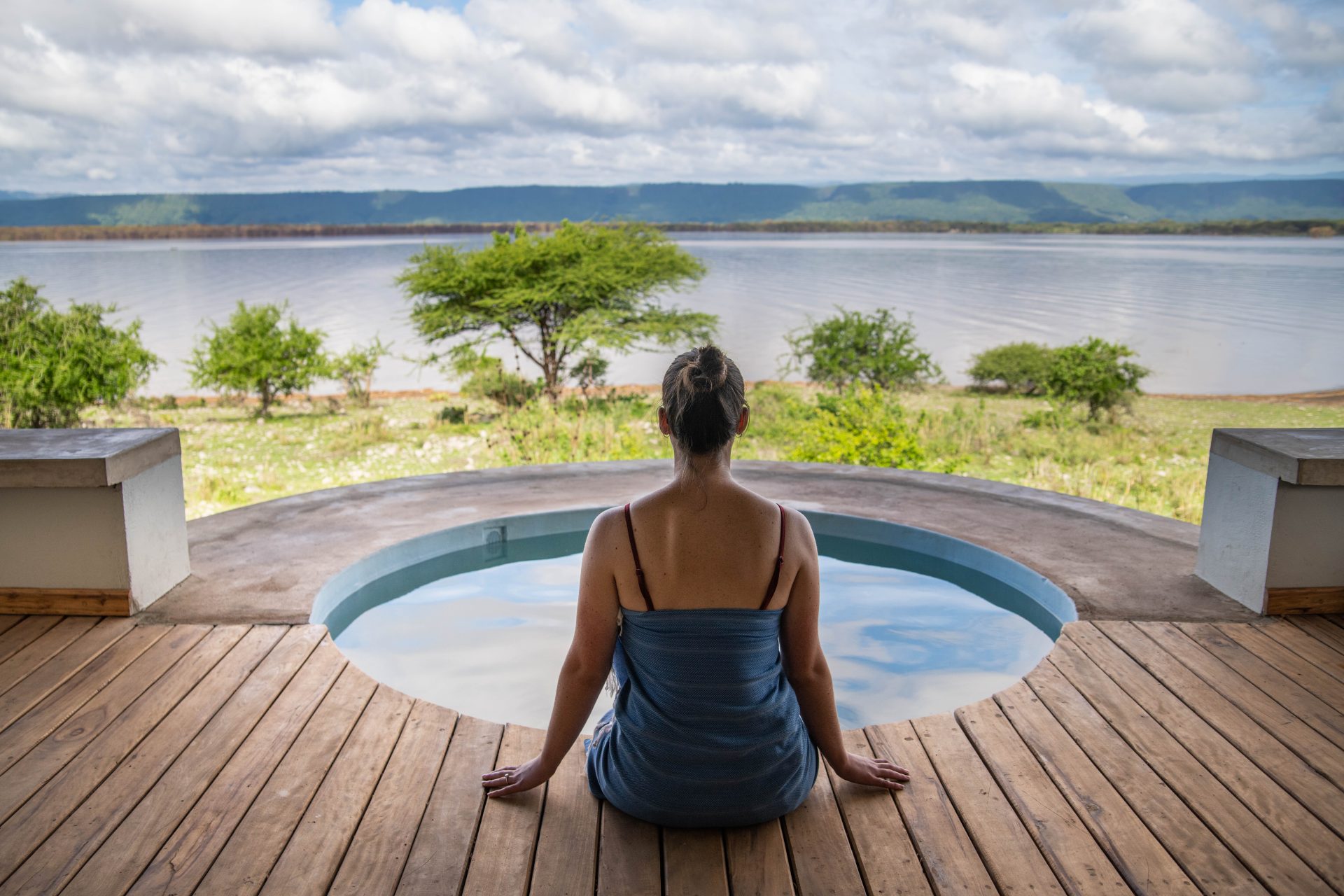 A client sitting on the edge of a lodge pool, looking out over the landscape in Tanzania.